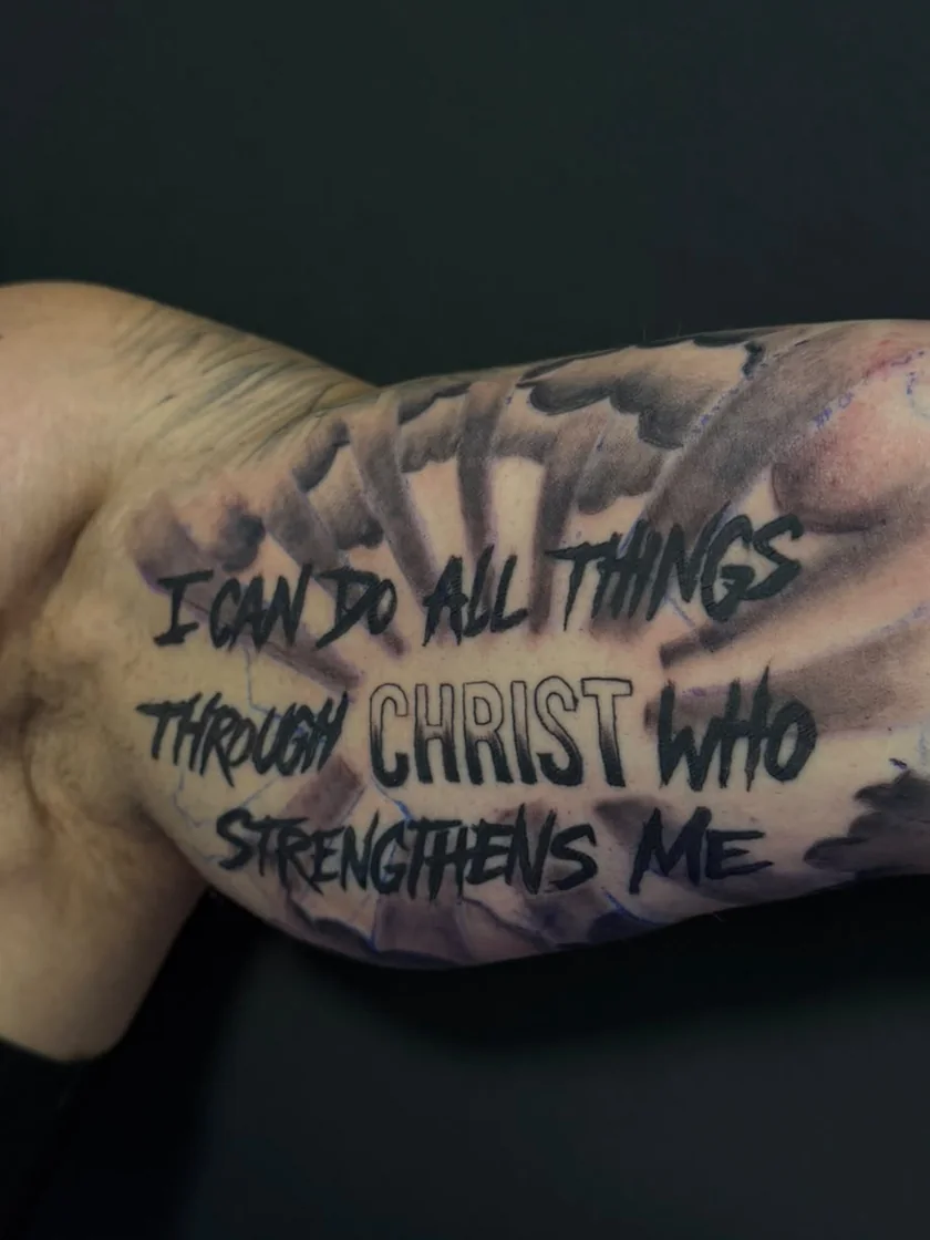 Schriftzug I can do all things through Christ who strengthens me mit Lichtstrahlen am Oberarm