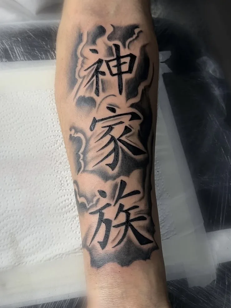 Schriftzeichen 神家族 mit Wolken auf dem Unterarm