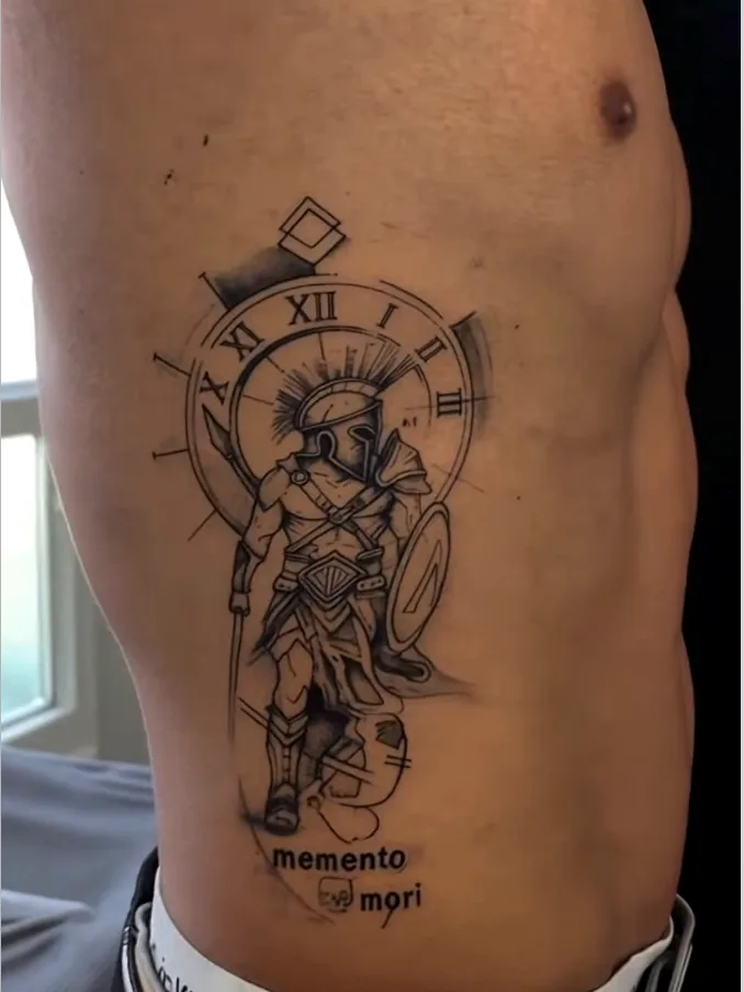 Spartaner mit Uhr und Schriftzug memento mori an den Rippen